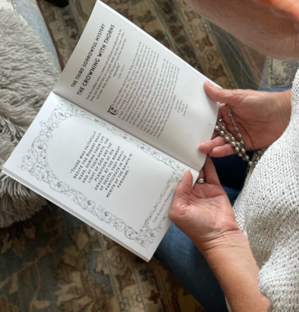 A woman kneeling and reflecting on the 15 Promises of the Rosary while holding Praying the Promises of the Rosary rosary devotional while holding a rosary