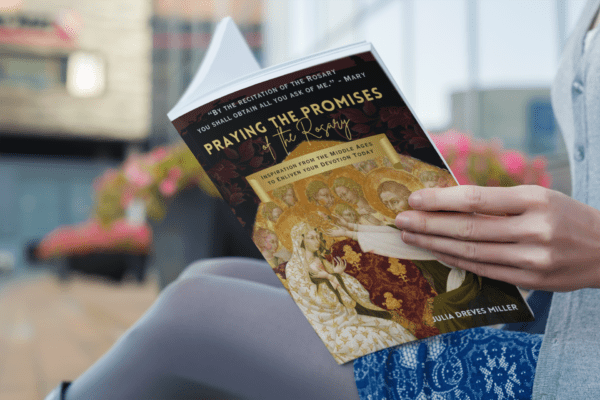 A woman holding the rosary devotional Praying the Promises of the Rosary